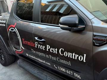 Door of a dark grey TermiteFree Pest Control ute with the company logo and 1300 617 506